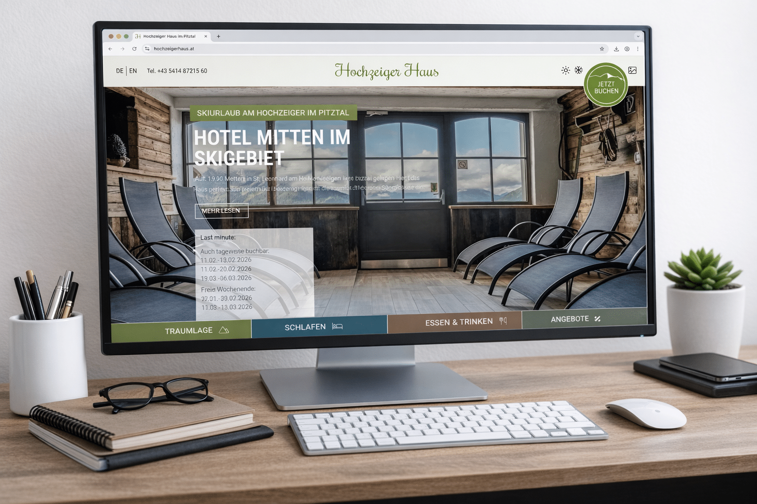 Auf einem Schreibtisch steht ein Monitor, Tastatur und Maus, sowie Büromaterial und Deko.