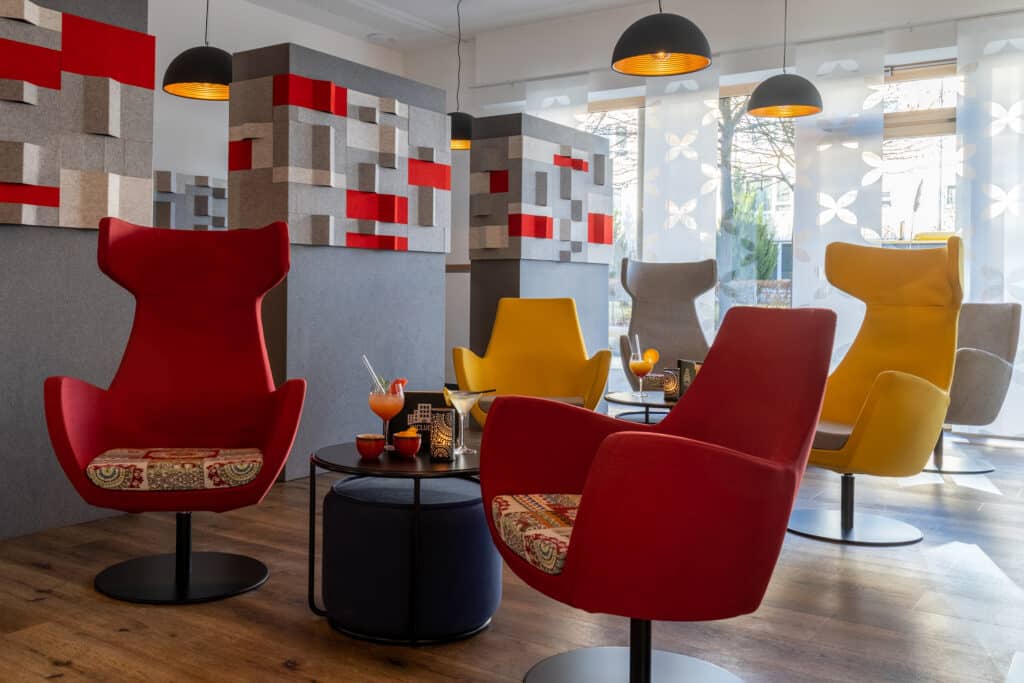 Gelbe und rote Stühle in der Lobby des Inklusionshotel INCLUDiO Regensburg
